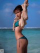 A woman in a blue bikini standing in the ocean.