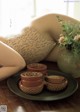 A woman laying on a table next to a vase of flowers.