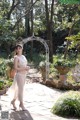 A woman in a white dress standing in a garden.